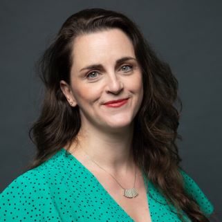 A white woman with long wavy brown and a green top