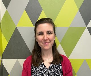 A young white woman with shoulder-length brown hair and a red cardigan